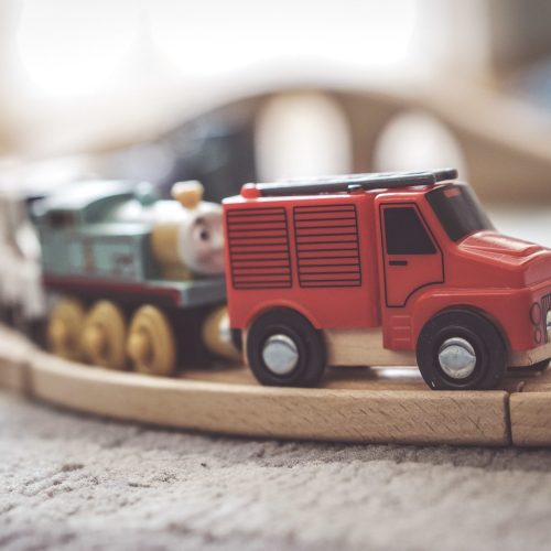 A closeup shot of a small toy car on a wooden train track
